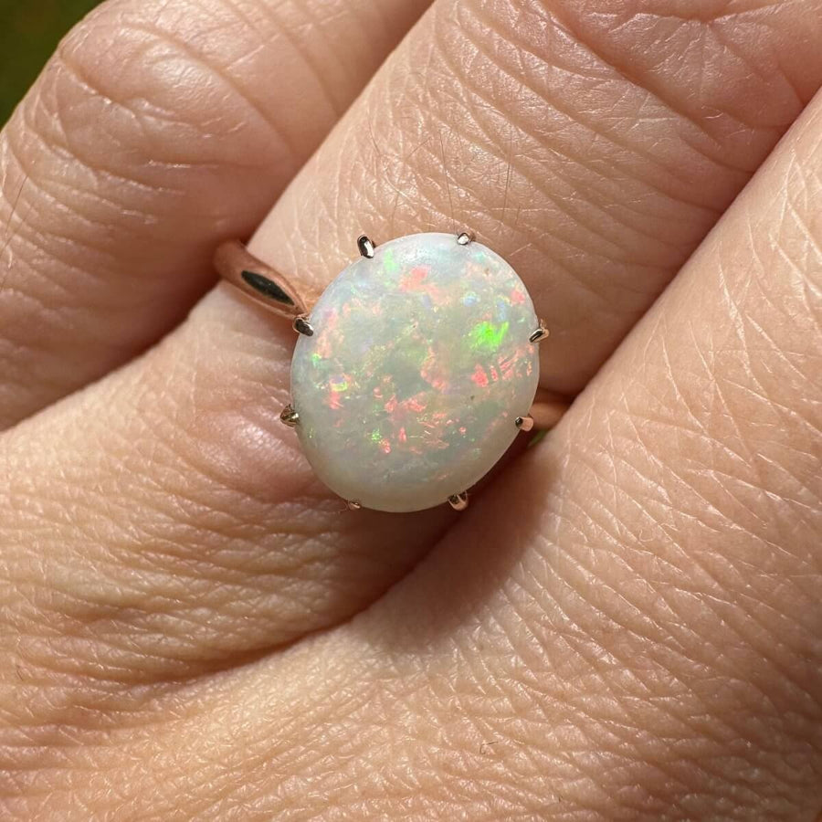 Art Deco 18ct gold ring featuring a stunning white opal with vibrant red, green, blue, and yellow hues.