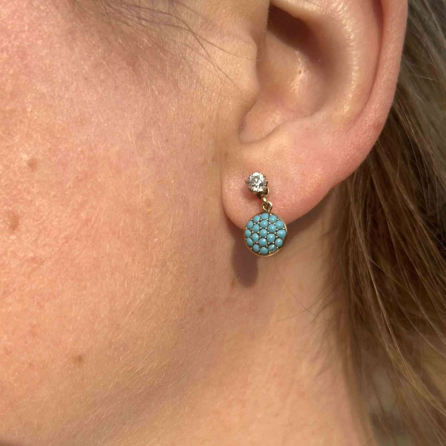 Close-up of early 20th-century gold diamond and pavé turquoise screw-on earrings worn on a model's ear.