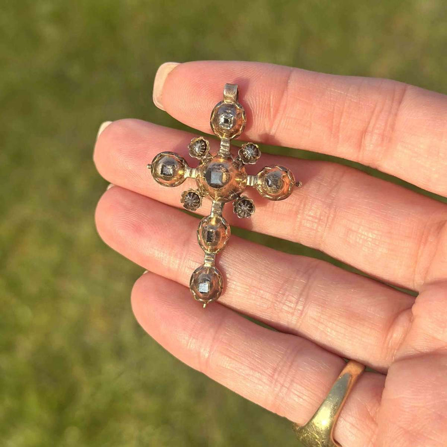 Early Georgian gold cross pendant with rose-cut diamonds, circa 1720, reflecting warm candlelight.