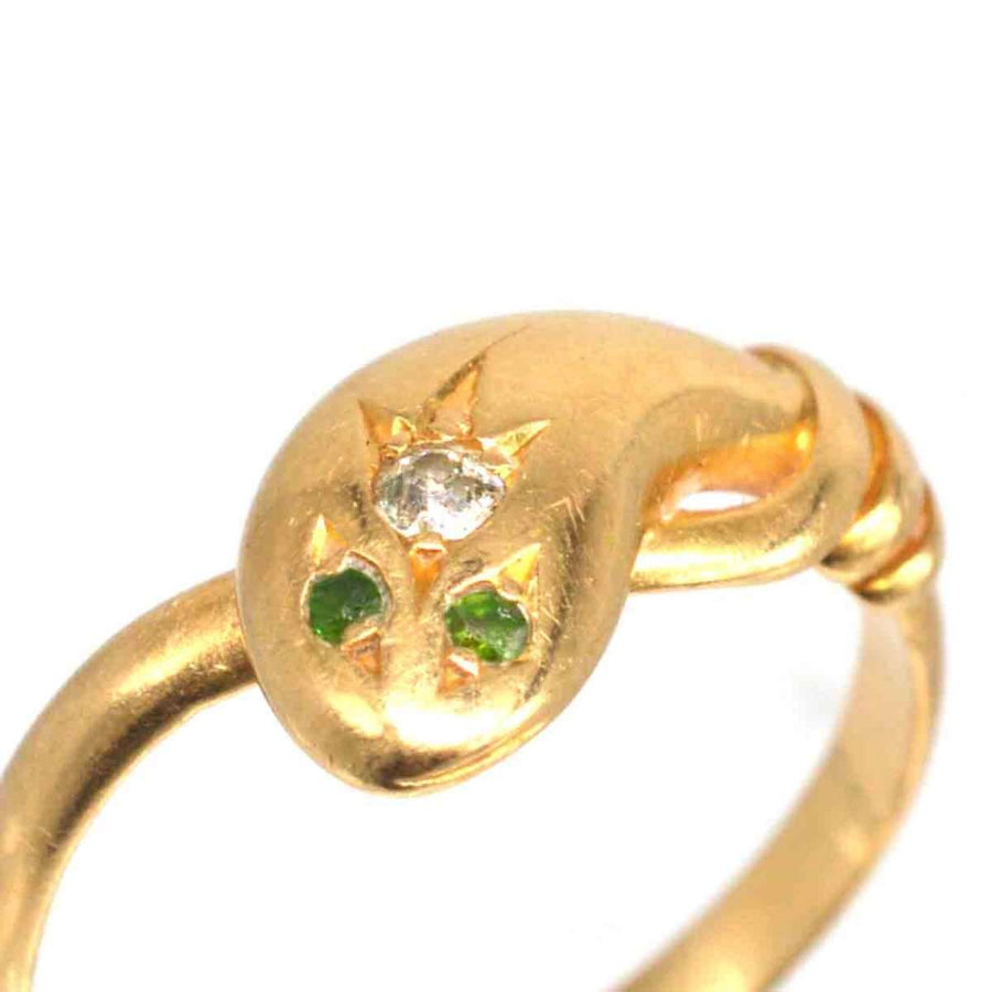 Edwardian 18ct gold snake ring featuring a diamond and two green garnet eyes, showcasing exquisite craftsmanship.