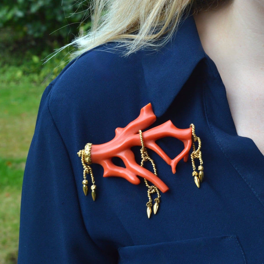 Large 19th century red coral brooch with gold tassels on a navy shirt, showcasing rocaille style elegance.