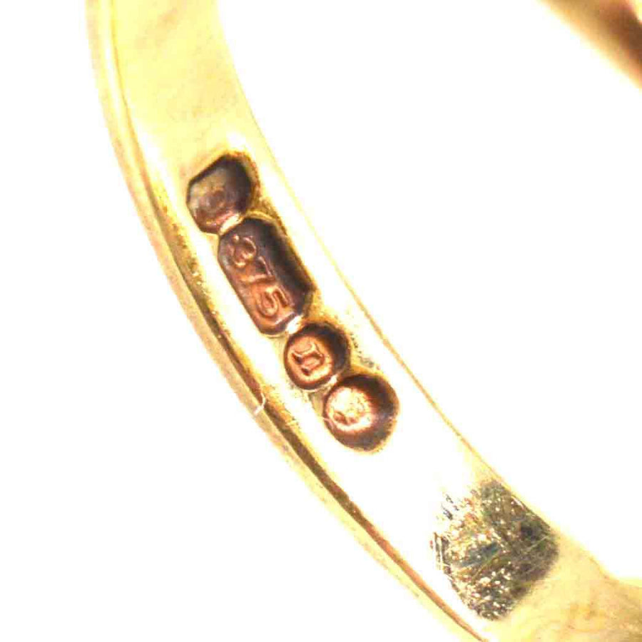 Close-up of the inner band of a 9ct gold ring featuring hallmark and purity stamp.