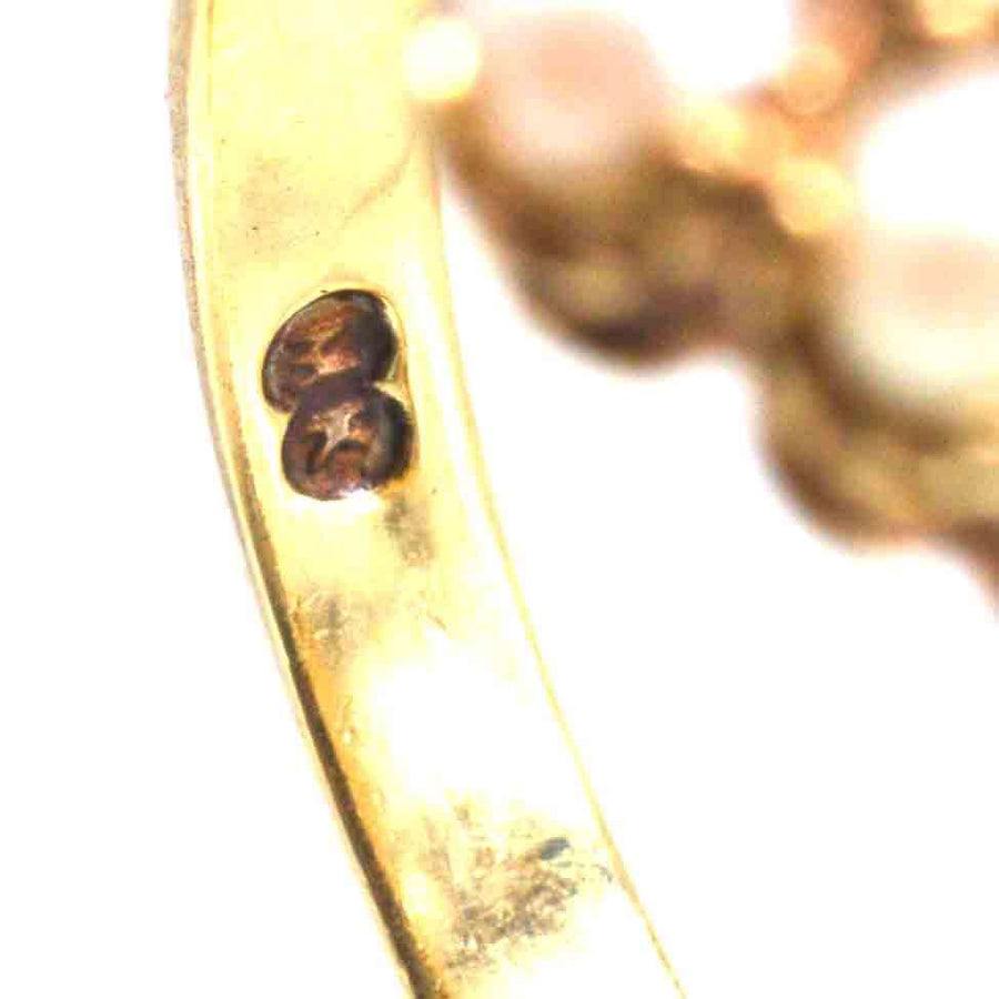 Close-up of the hallmark on a Late Victorian 9ct gold split pearl and diamond ring, showcasing craftsmanship details.