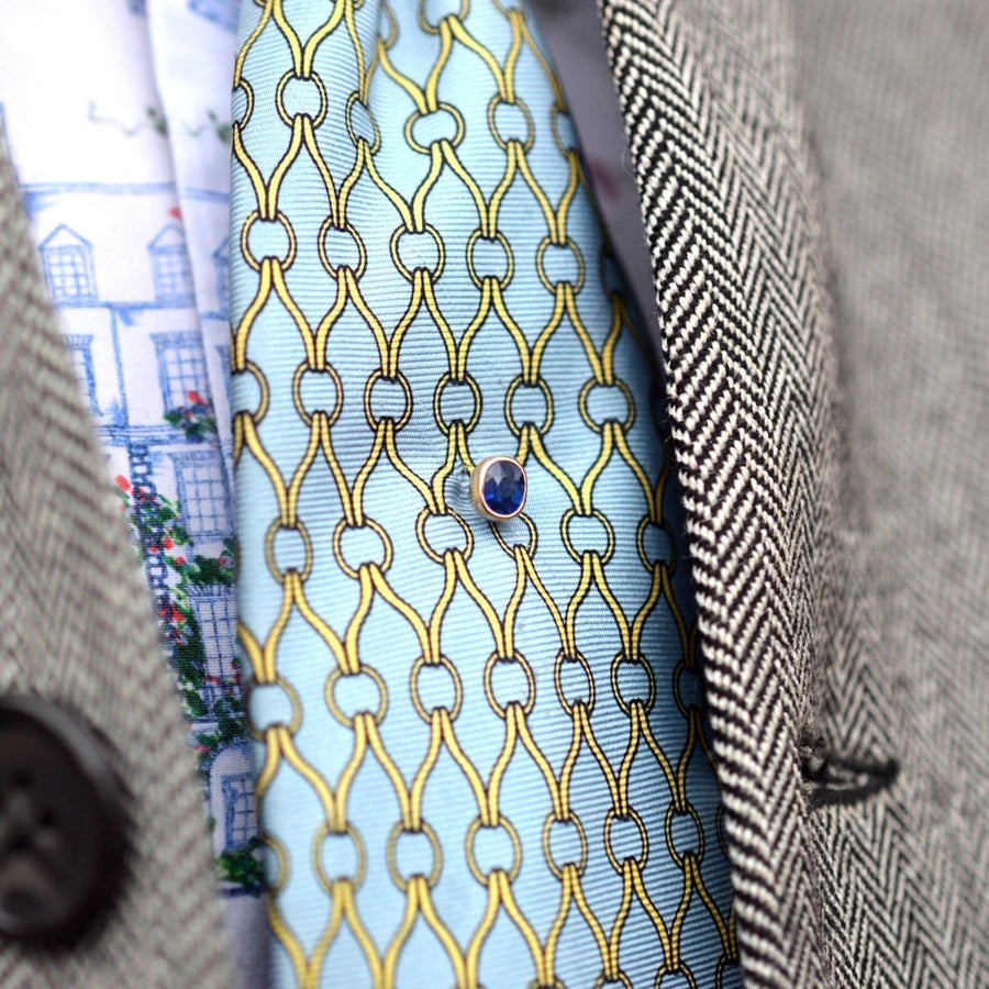 Austro-Hungarian 14ct gold sapphire tie pin on a colorful silk tie, showcasing fine craftsmanship and timeless design.
