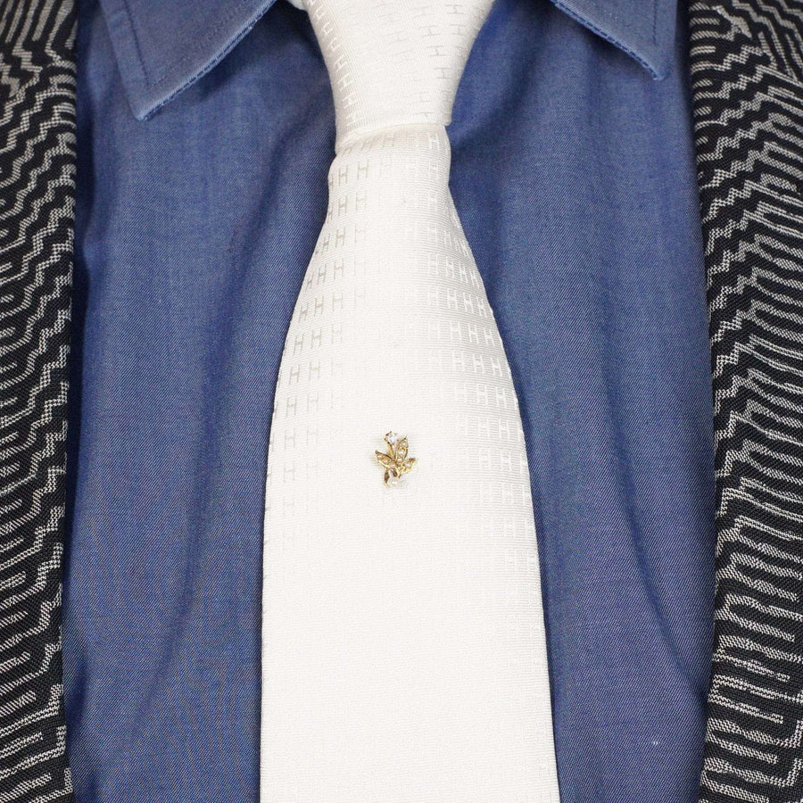 Edwardian 14ct gold tie pin featuring natural pearl leaves and a diamond flower, styled on a white tie.
