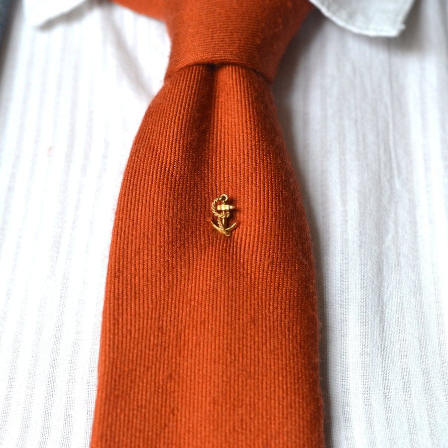 15ct gold ship anchor and rope tie pin on an orange tie, symbolizing enduring bonds and perfect for weddings.