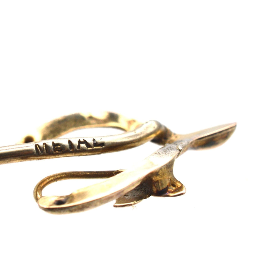 Close-up of an antique Edwardian 9ct gold wishbone tie pin with ivy leaf detail, symbolizing love and good fortune.