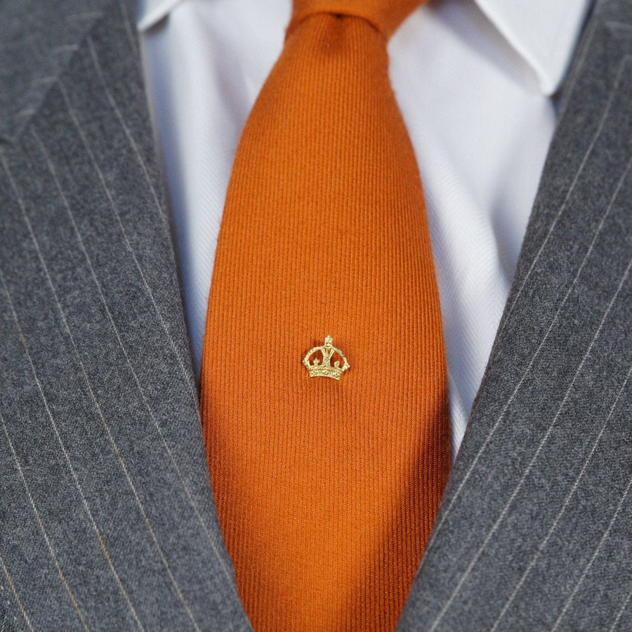 Late 1930s Royal Imperial State Crown tie pin on an orange silk tie, worn with a gray pinstriped suit.