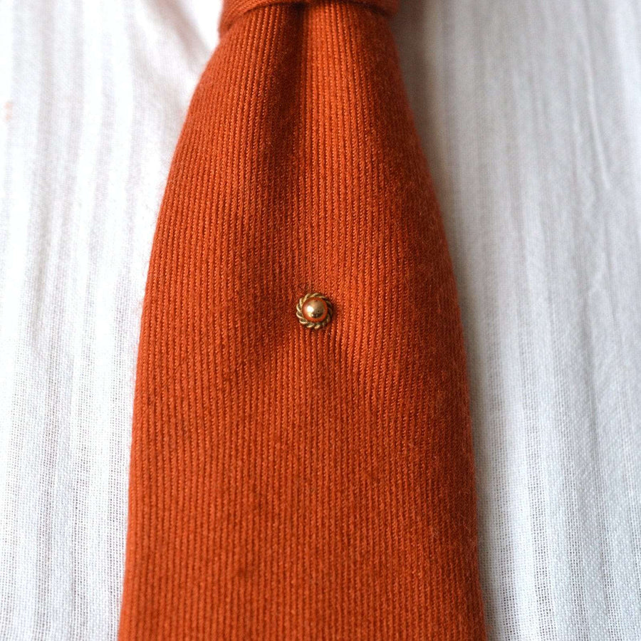 Victorian 9ct gold simple knot and ball tie pin on an orange silk tie, showcasing a classic and subtle elegance.